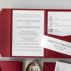 Czerwone zaproszenia ślubne z imionami Amelia i Mateusz, datą i ikonami.