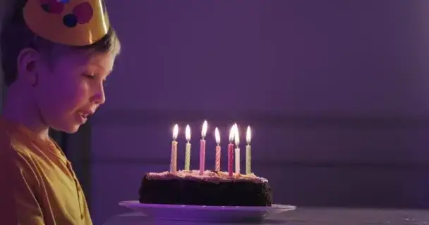dziecko zdmuchujące pierwszą świeczkę na torcie urodzinowym
